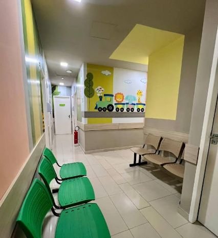 Corredor de espera com cadeiras verdes e parede decorada com tema infantil
